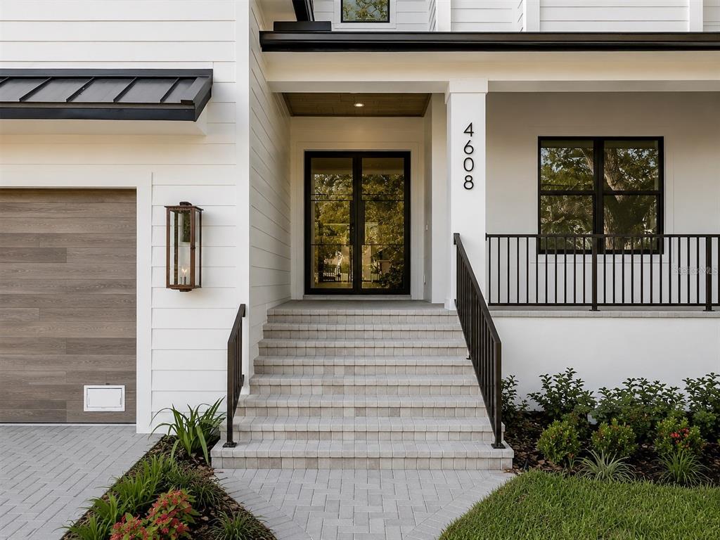 The exterior of a modern white house features a brick staircase leading to double doors — 4608 W EL PRADO BOULEVARD, TAMPA, FL