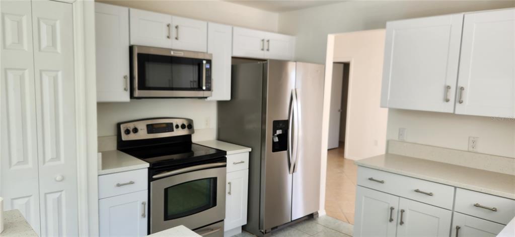 A kitchen features white cabinets, stainless steel appliances, and light-colored countertops — 2856 TRENTON LANE, DELTONA, FL