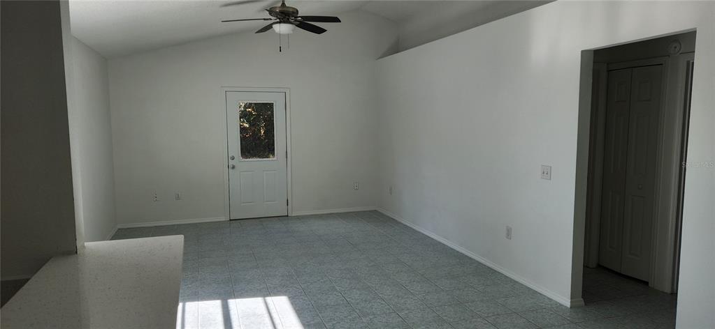 An empty room with white walls, tile flooring, a ceiling fan, and a glass-paneled door — 2856 TRENTON LANE, DELTONA, FL