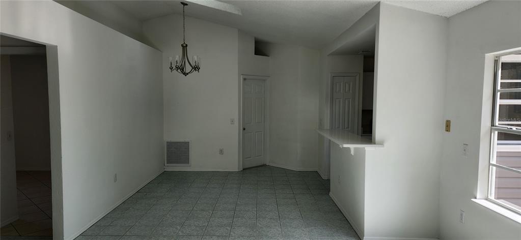 A dining area with tile flooring, a chandelier, and a breakfast bar opening to a kitchen — 2856 TRENTON LANE, DELTONA, FL