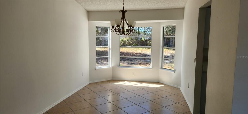 A dining area with tile flooring, a chandelier, and a bay window overlooking a yard — 2856 TRENTON LANE, DELTONA, FL