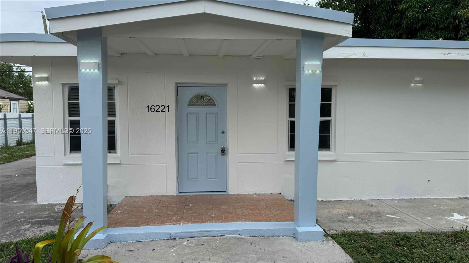 The exterior of a white house features a light blue front door and porch columns — 16221 E Bunche Park Dr, Miami Gardens FL 33054, MIAMI GARDENS, FL