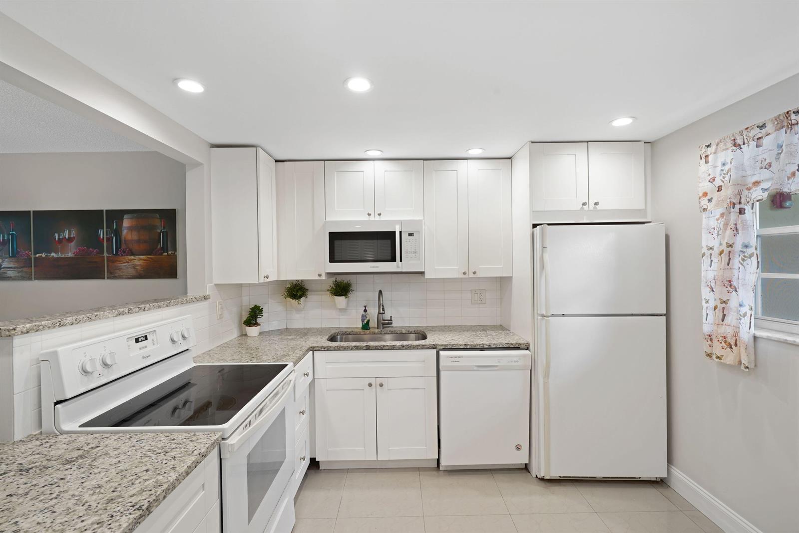 A kitchen with white cabinets, granite countertops, stainless steel appliances, and a tiled backsplash — 100 Berkley Road # 109, Hollywood FL 33024, HOLLYWOOD, FL