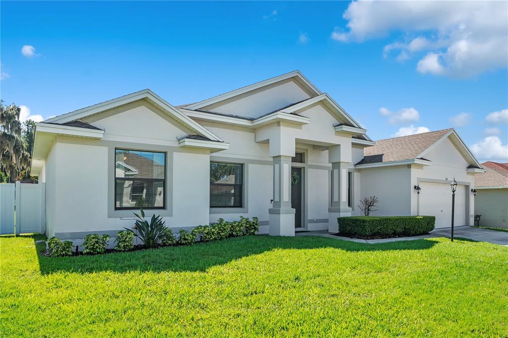 A single-story house with a white stucco exterior, a front porch, and a two-car garage — 525 GANDHI DRIVE, LAKELAND, FL