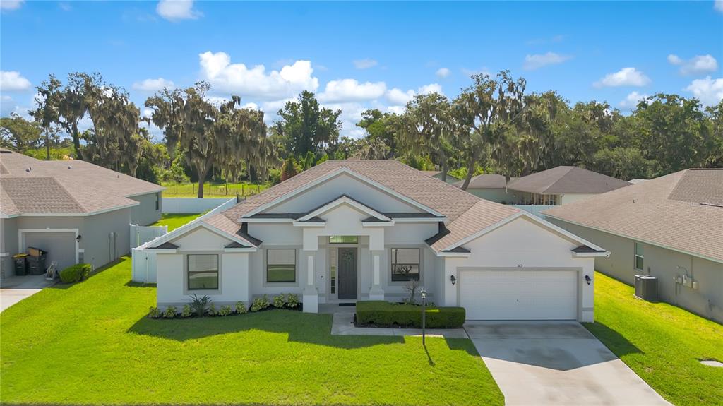 A single-story suburban house with a two-car garage, light-colored stucco exterior, and a shingled roof — 525 GANDHI DRIVE, LAKELAND, FL