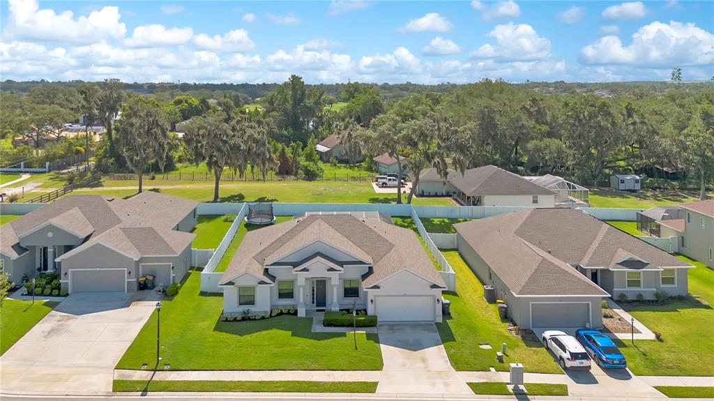 An aerial view shows three suburban houses with attached garages and green lawns — 525 GANDHI DRIVE, LAKELAND, FL