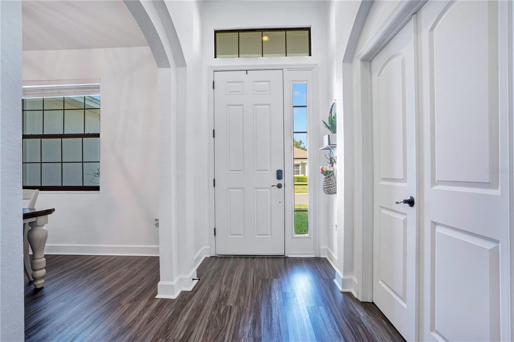 A bright entryway features white walls, wood-look flooring, a front door with sidelights, and an arched opening — 525 GANDHI DRIVE, LAKELAND, FL