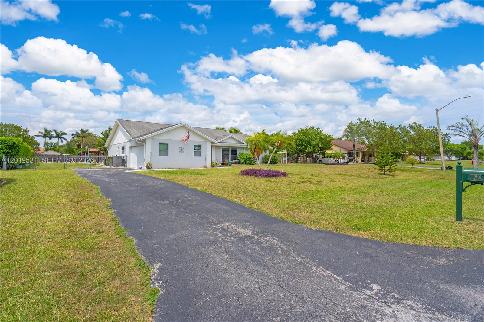 This open-concept living area features a blue kitchen island, dining space, and gray sofa — 1501 NW 20th St, Homestead FL 33030, HOMESTEAD, FL