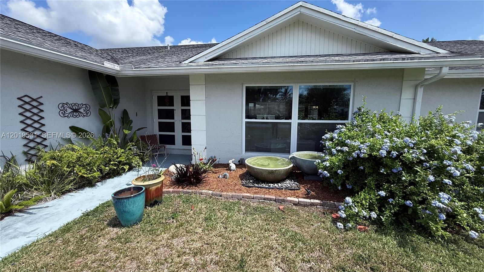An open-concept living area features a grey sofa, yellow chairs, and a blue kitchen island — 1501 NW 20th St, Homestead FL 33030, HOMESTEAD, FL