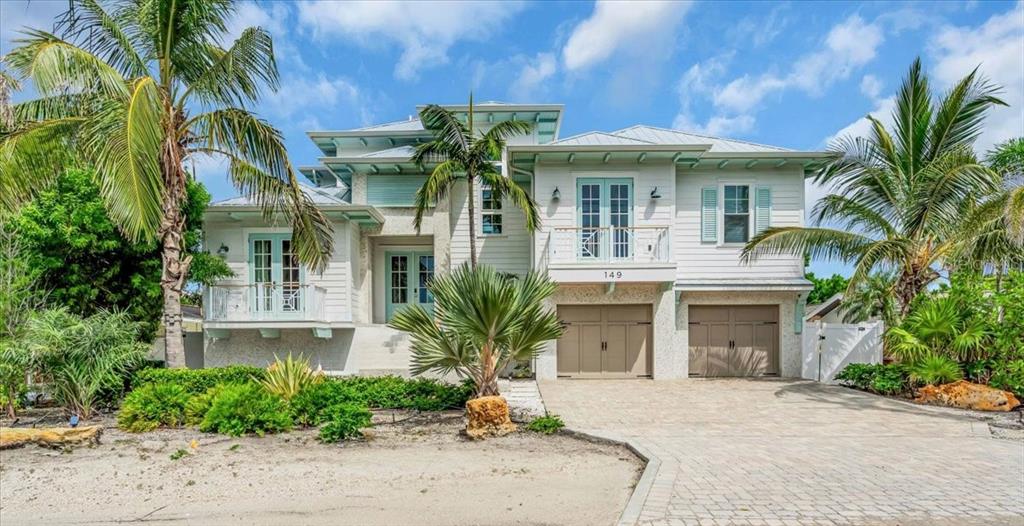 A two-story coastal home features light siding, a paved driveway, and several palm trees — 149 MCKINLEY DRIVE, SARASOTA, FL