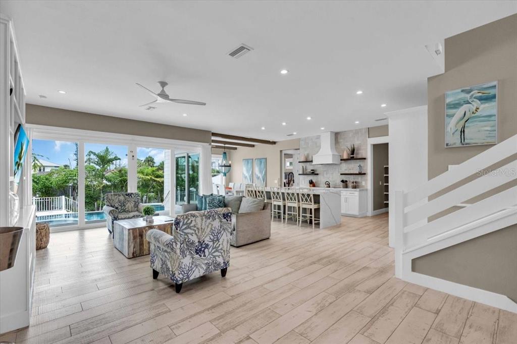 An open-concept living room and kitchen feature light wood flooring, white cabinetry, and pool views — 149 MCKINLEY DRIVE, SARASOTA, FL