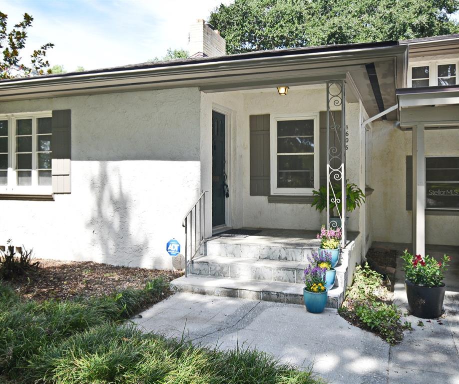 The exterior of a white stucco house features a covered front porch with stone steps — 1606 ORANGEWOOD AVENUE, ORLANDO, FL