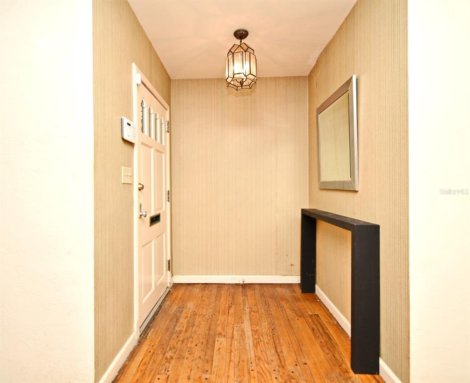 An entryway features hardwood floors, vertical striped wallpaper, a hanging lantern light, and a console table — 1606 ORANGEWOOD AVENUE, ORLANDO, FL