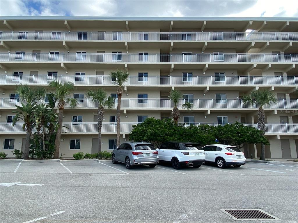 A multi-story apartment building with white balconies stands behind a paved parking lot — 2401 S ATLANTIC AVENUE UNIT E204, NEW SMYRNA BEACH, FL