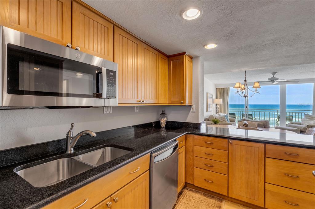 A kitchen with wood cabinets, black granite countertops, and a view of the ocean — 2401 S ATLANTIC AVENUE UNIT E204, NEW SMYRNA BEACH, FL