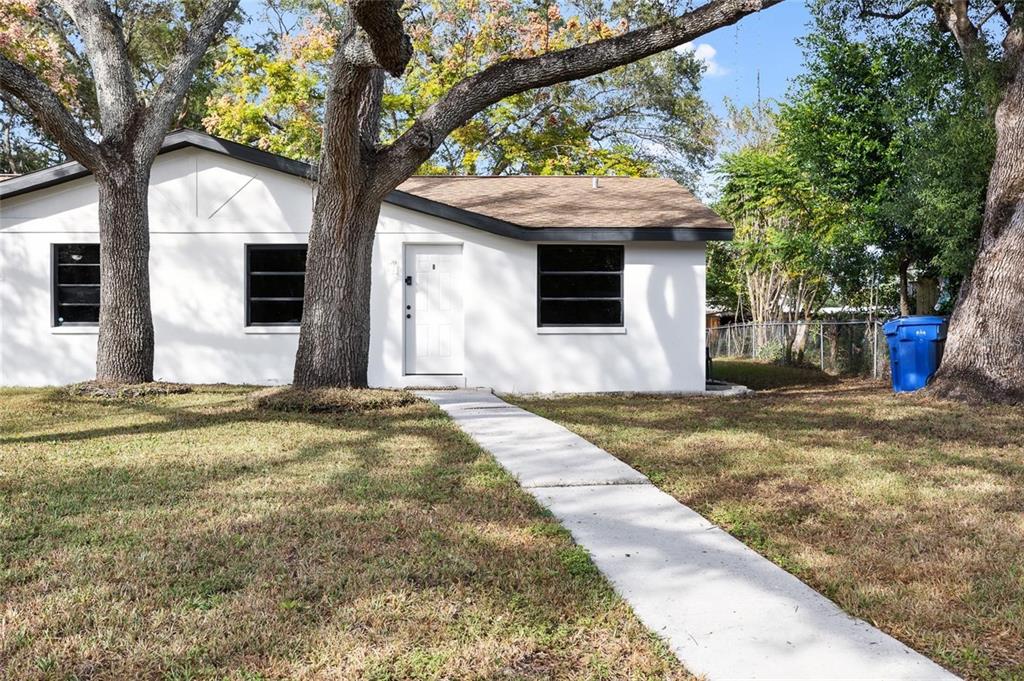 A white single-story house with a brown roof, black window frames, and a concrete walkway — 1220 E 142ND AVENUE UNIT B, TAMPA, FL