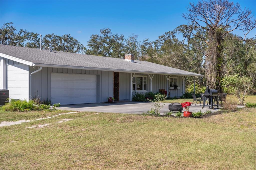 A single-story house with gray vertical siding, a white garage door, and a concrete patio — 1510 LENA LANE, SARASOTA, FL