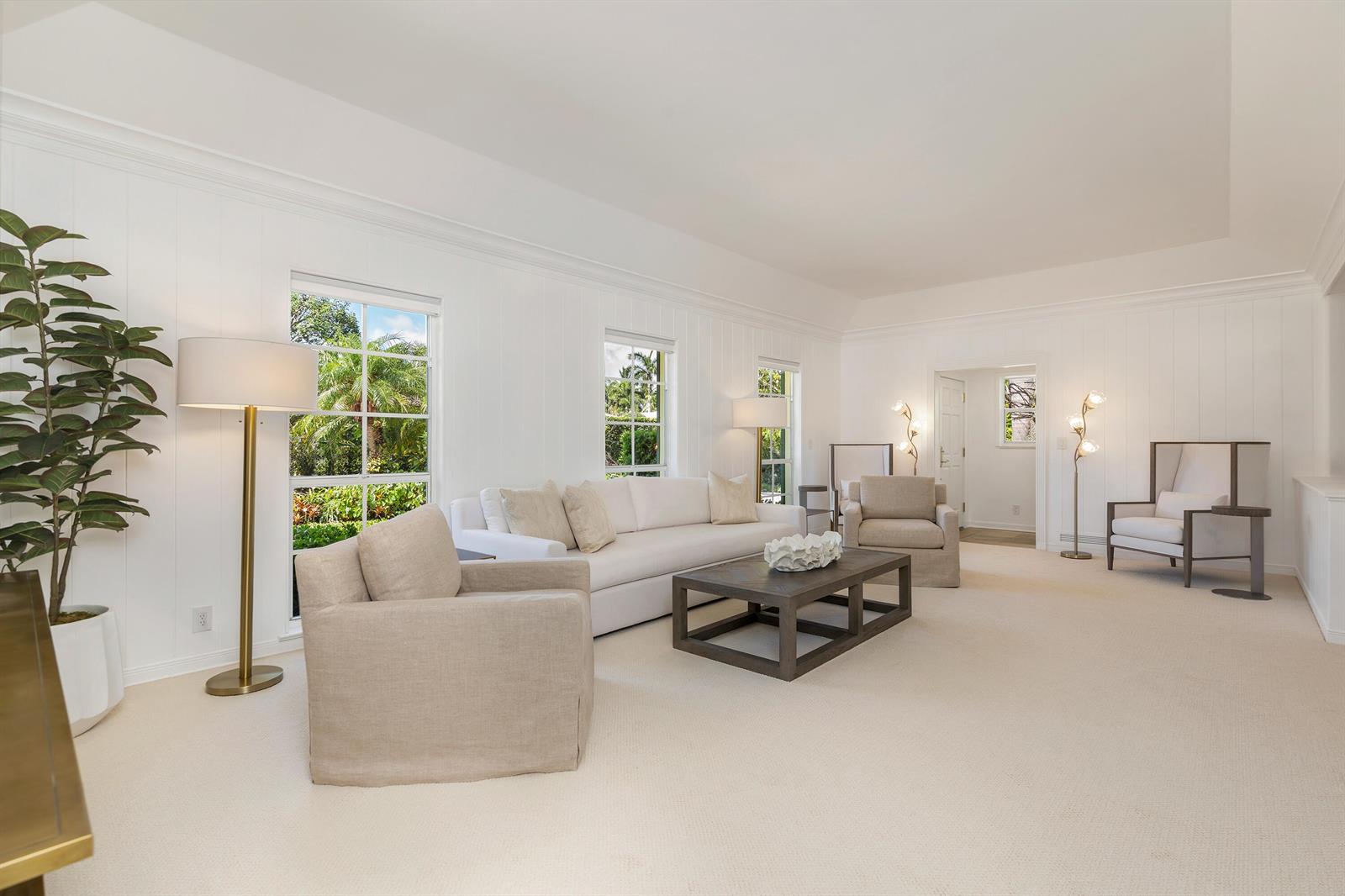 A bright living room features white paneled walls, a white sofa, and beige armchairs — 241 Via Linda, Palm Beach FL 33480, PALM BEACH, FL