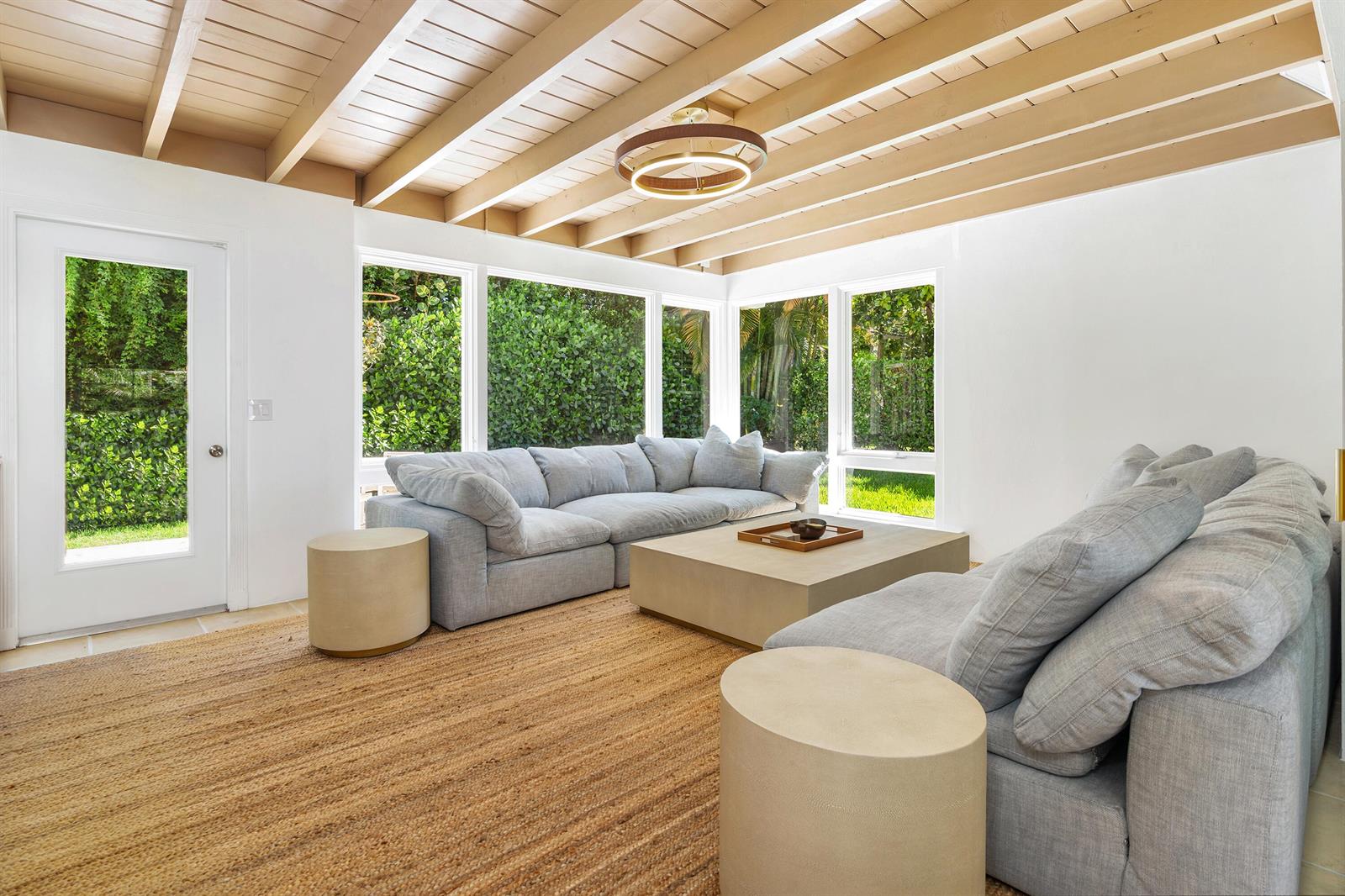 A sunroom features a light gray sectional sofa, a large coffee table, and exposed ceiling beams — 241 Via Linda, Palm Beach FL 33480, PALM BEACH, FL