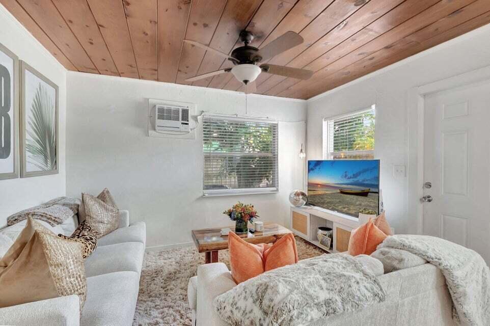 A living room features a wood-paneled ceiling, white walls, and two sofas facing a television — 329 SE 3rd Avenue, Delray Beach FL 33483, DELRAY BEACH, FL