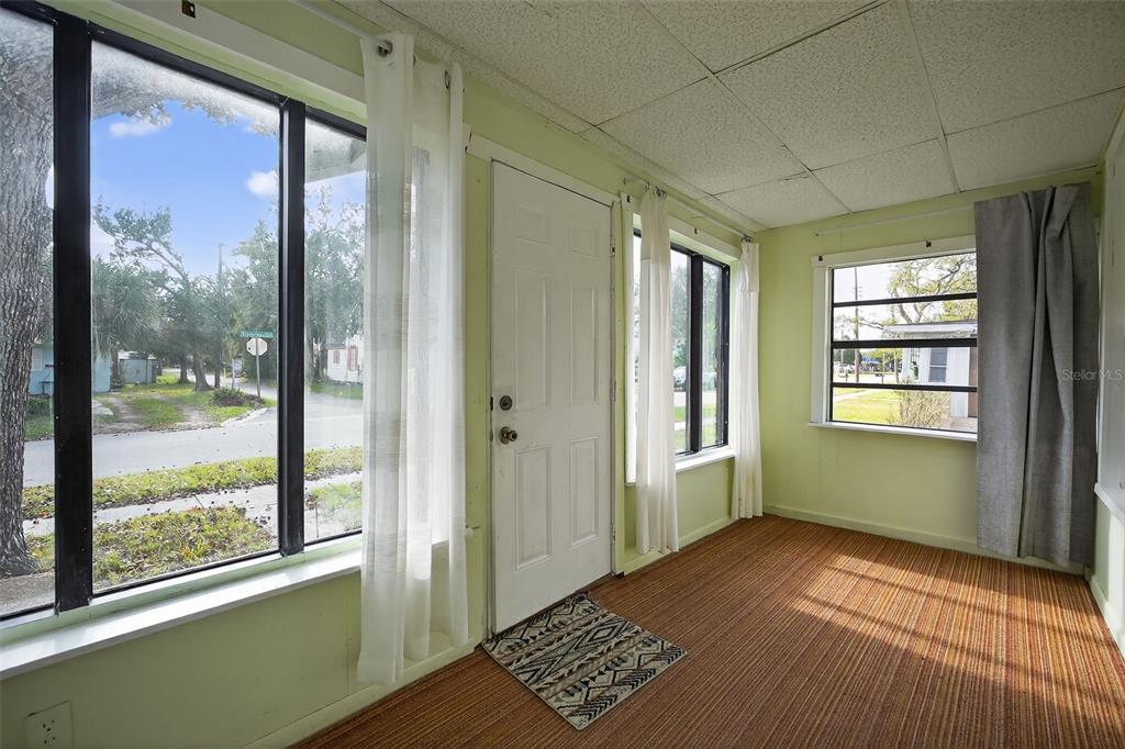 A sunroom features light green walls, striped carpet, a white door, and large windows — 146 KINGSTON AVENUE, DAYTONA BEACH, FL