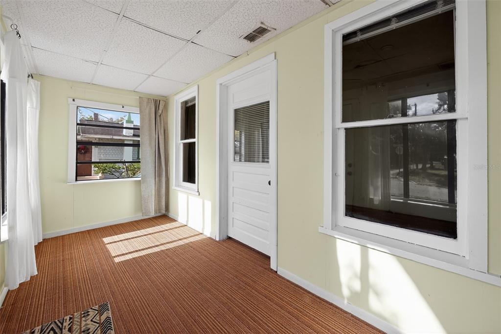 A sunroom with pale yellow walls, a drop ceiling, and brown carpeted flooring — 146 KINGSTON AVENUE, DAYTONA BEACH, FL