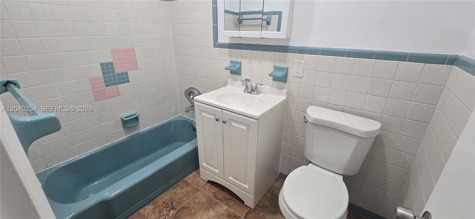 A bathroom features a blue bathtub, a white vanity, a toilet, and tiled walls — 201 SW 30th Ct, Miami FL 33135, MIAMI, FL