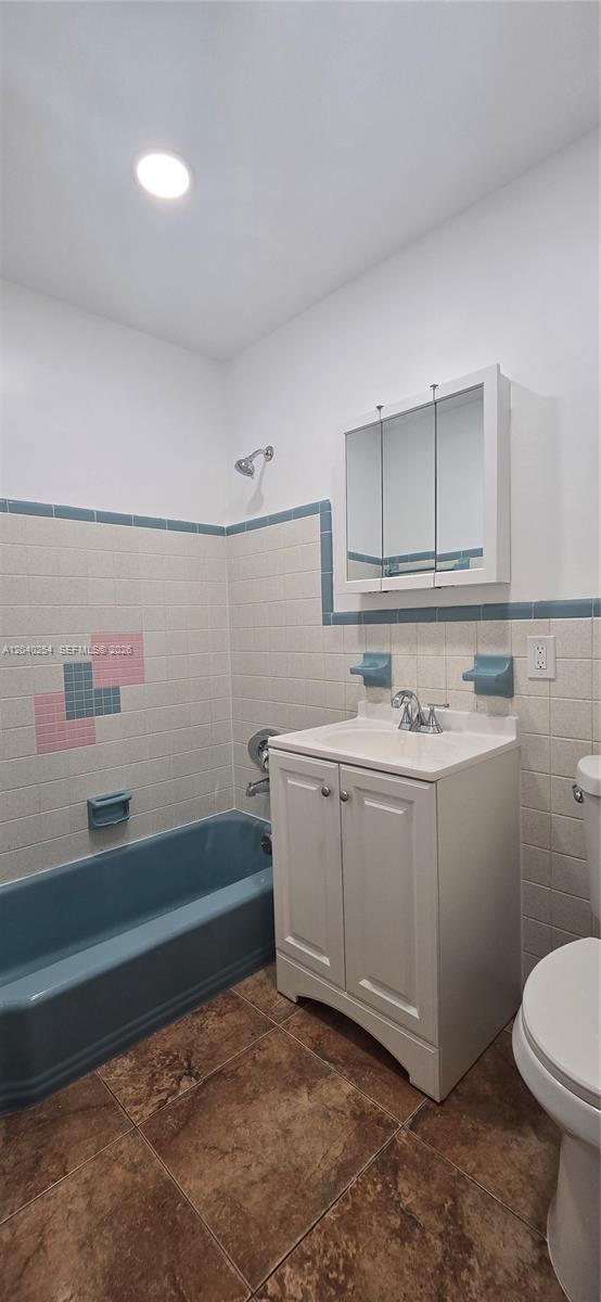 A bathroom features a blue bathtub, a white vanity, and tiled walls with decorative accents — 201 SW 30th Ct, Miami FL 33135, MIAMI, FL