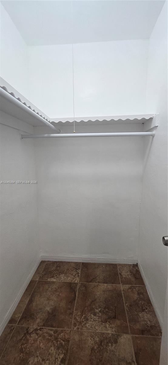 A small walk-in closet features white walls, a single shelf, a hanging rod, and tiled flooring — 201 SW 30th Ct, Miami FL 33135, MIAMI, FL