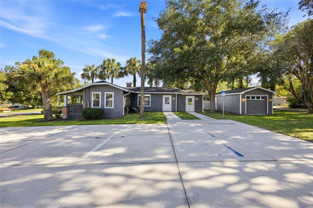 A gray single-story house with a detached garage and a large concrete parking area — 527 NE 8TH AVENUE, OCALA, FL