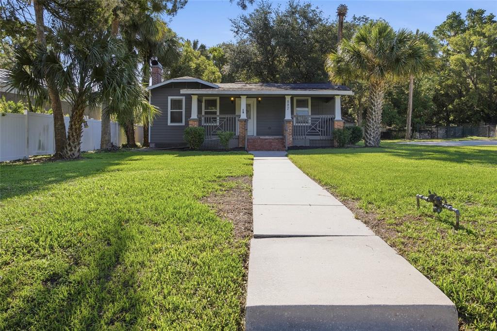 A gray single-story house with a front porch and a concrete walkway across the lawn — 527 NE 8TH AVENUE, OCALA, FL