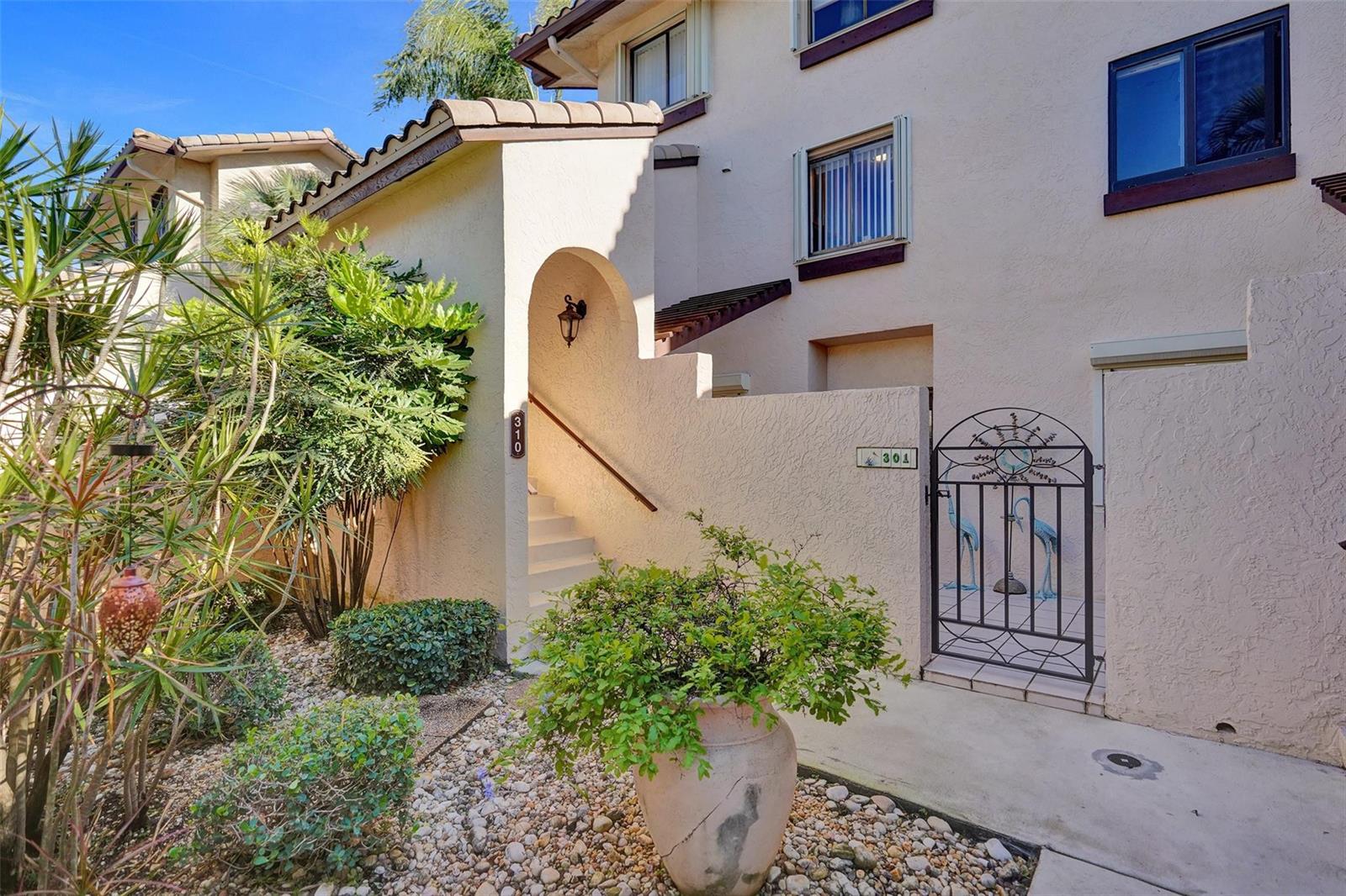 An exterior view shows a stucco building with a gated entrance and a staircase — 270 Captains Walk # 310, Delray Beach FL 33483, DELRAY BEACH, FL