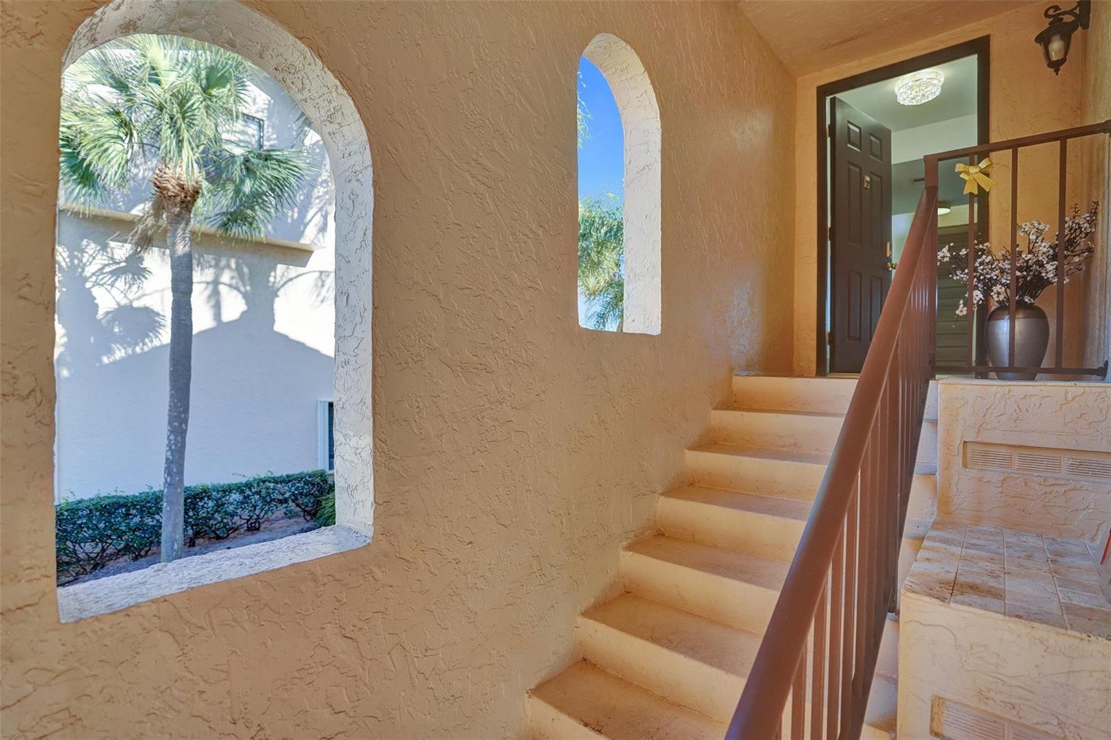An outdoor staircase leads to an entryway with arched windows and textured beige walls — 270 Captains Walk # 310, Delray Beach FL 33483, DELRAY BEACH, FL