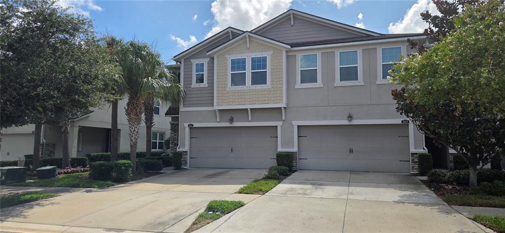 A two-story townhouse with a two-car garage and a beige stucco exterior — 10322 HOLSTEIN EDGE PLACE, RIVERVIEW, FL
