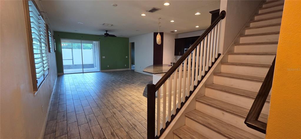 An open-concept living area features wood-look tile flooring, a staircase, and a kitchen island — 10322 HOLSTEIN EDGE PLACE, RIVERVIEW, FL