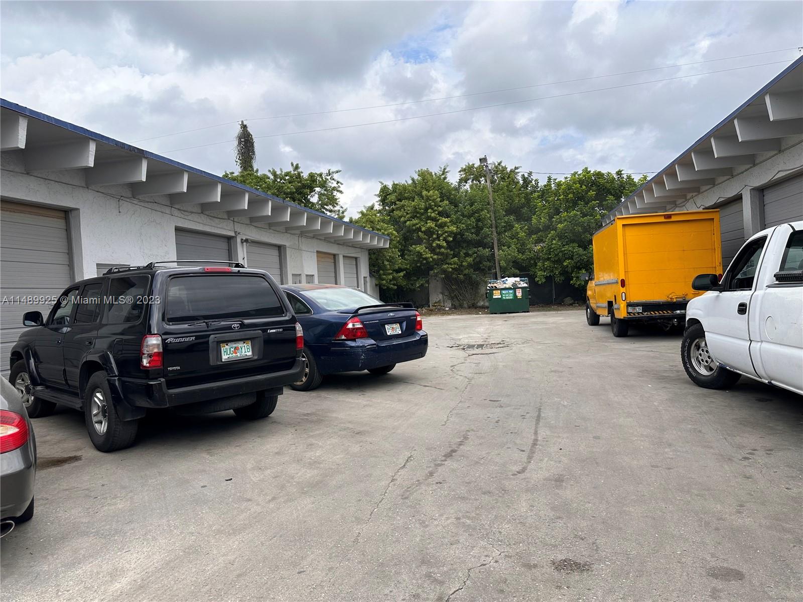 A paved parking lot sits between two industrial buildings with a yellow truck and cars — 5801-5807 Dawson St, Hollywood FL 33023, HOLLYWOOD, FL