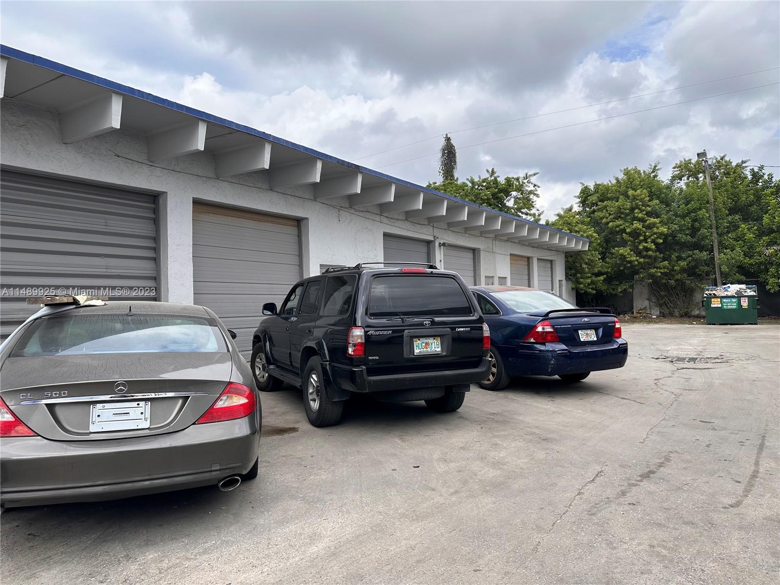 A row of garage bays with three parked cars in front of a white building — 5801-5807 Dawson St, Hollywood FL 33023, HOLLYWOOD, FL