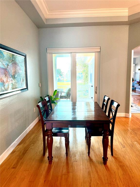 A dining room features a wooden table, four chairs, hardwood floors, and a sliding glass door — 2008 N POINTE ALEXIS DRIVE, TARPON SPRINGS, FL