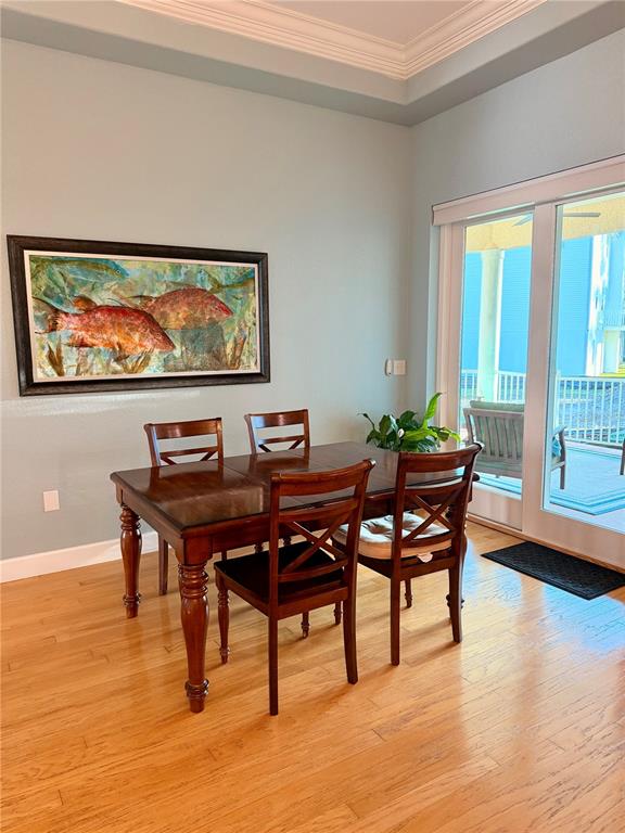 A dining room features a wooden table, four chairs, a fish painting, and sliding glass doors — 2008 N POINTE ALEXIS DRIVE, TARPON SPRINGS, FL