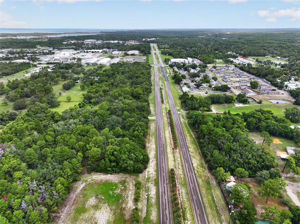 An aerial view shows a divided highway running through a wooded area with nearby buildings — 0 S LITTLE ROAD S, HUDSON, FL