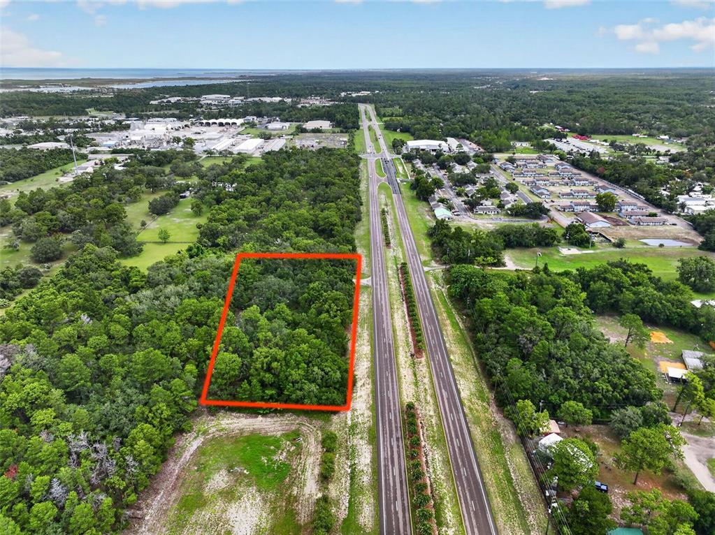 An aerial view shows a rectangular wooded lot outlined in red next to a highway — 0 S LITTLE ROAD S, HUDSON, FL