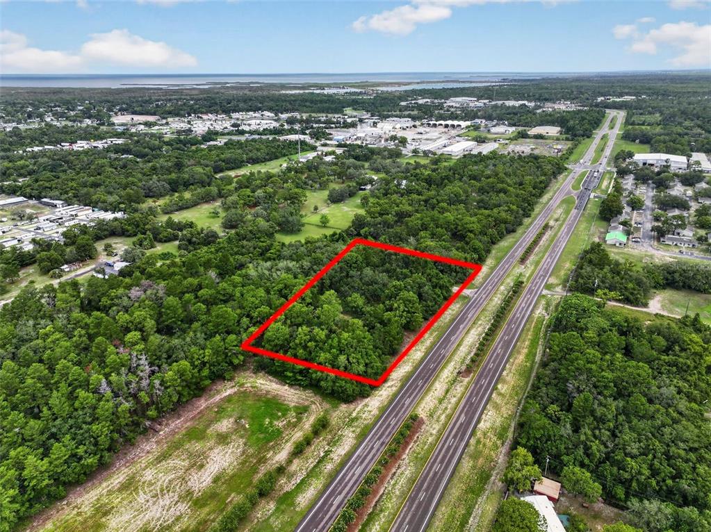 An aerial view shows a rectangular plot of wooded land outlined in red beside a highway — 0 S LITTLE ROAD S, HUDSON, FL