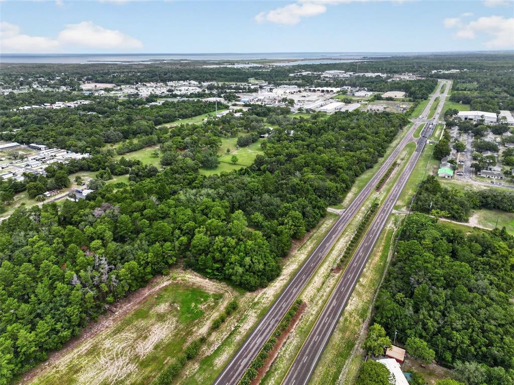 An aerial view shows a multi-lane highway running alongside a large, wooded plot of land — 0 S LITTLE ROAD S, HUDSON, FL