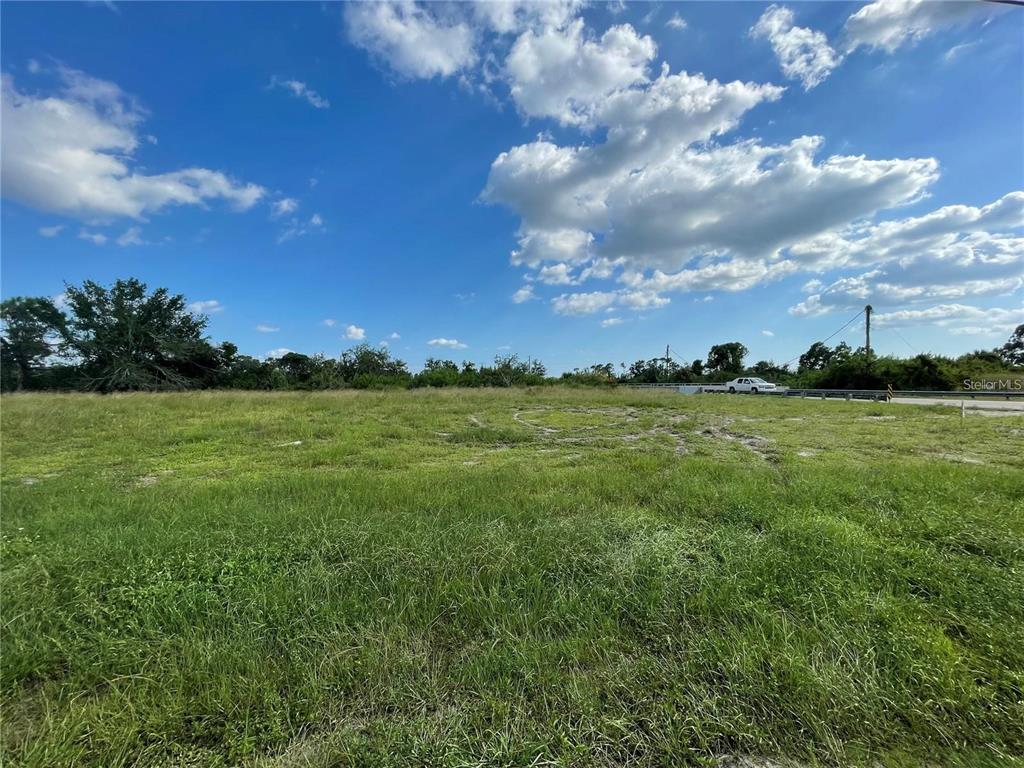 A wide, grassy vacant lot under a bright blue sky with scattered clouds — 12743 FORESMAN BLVD, PORT CHARLOTTE, FL