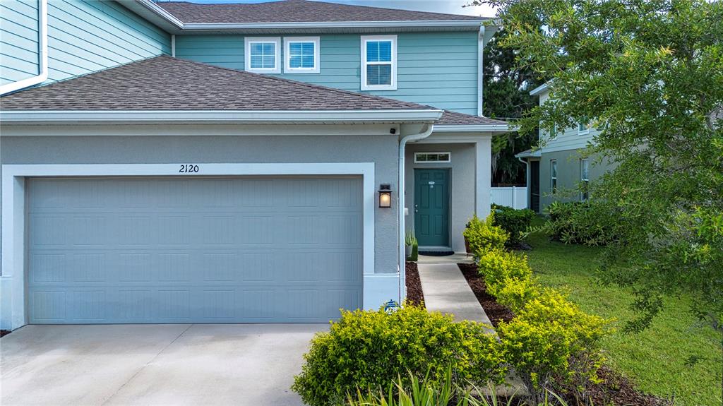 A two-story house features a light blue exterior, a gray garage door, and a front entrance — 2120 LACEFLOWER DRIVE, BRANDON, FL
