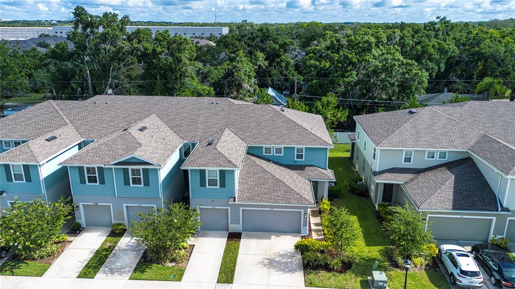 An aerial view shows several attached townhomes with gray roofs and teal or beige siding — 2120 LACEFLOWER DRIVE, BRANDON, FL