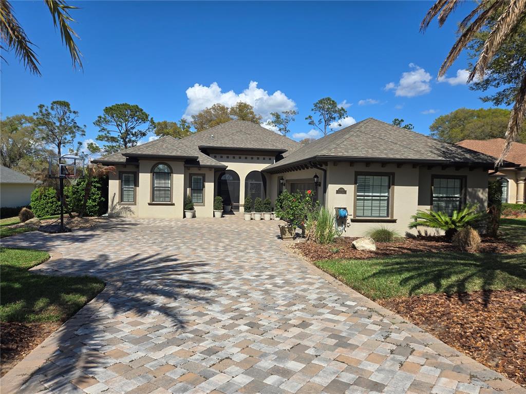 A single-story house with a paved driveway, arched entryway, and a hip roof — 5084 GREENS DRIVE, LADY LAKE, FL