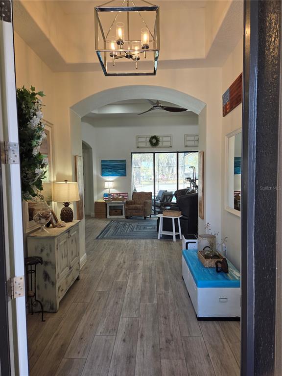 A view from a doorway into a foyer leading to a living room with wood-look flooring — 5084 GREENS DRIVE, LADY LAKE, FL