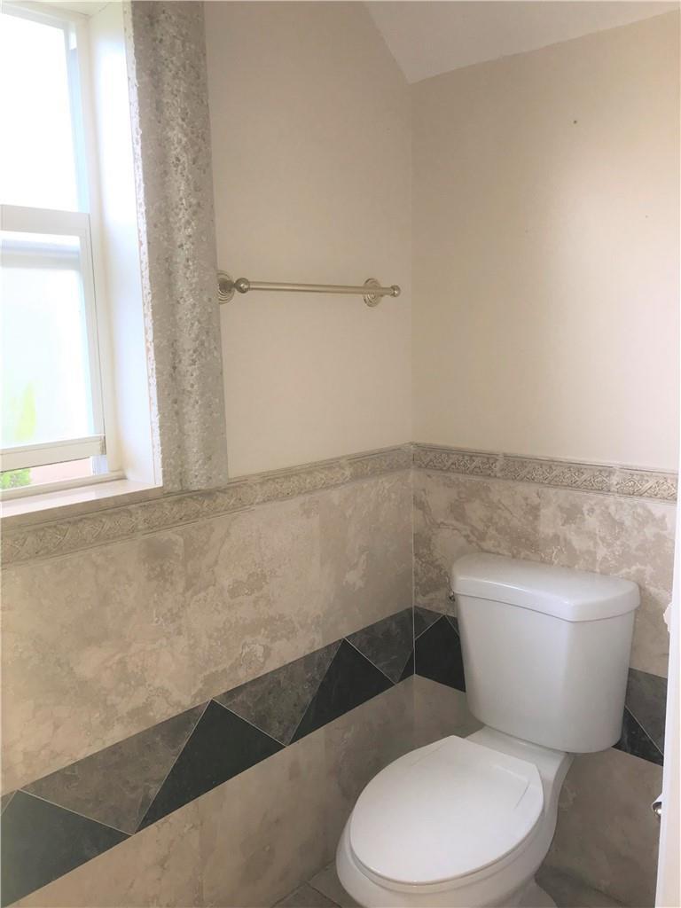 A bathroom features a toilet, a window, and walls with beige tile and a decorative border — 5449 NW 90th Avenue, Sunrise FL 33351, SUNRISE, FL