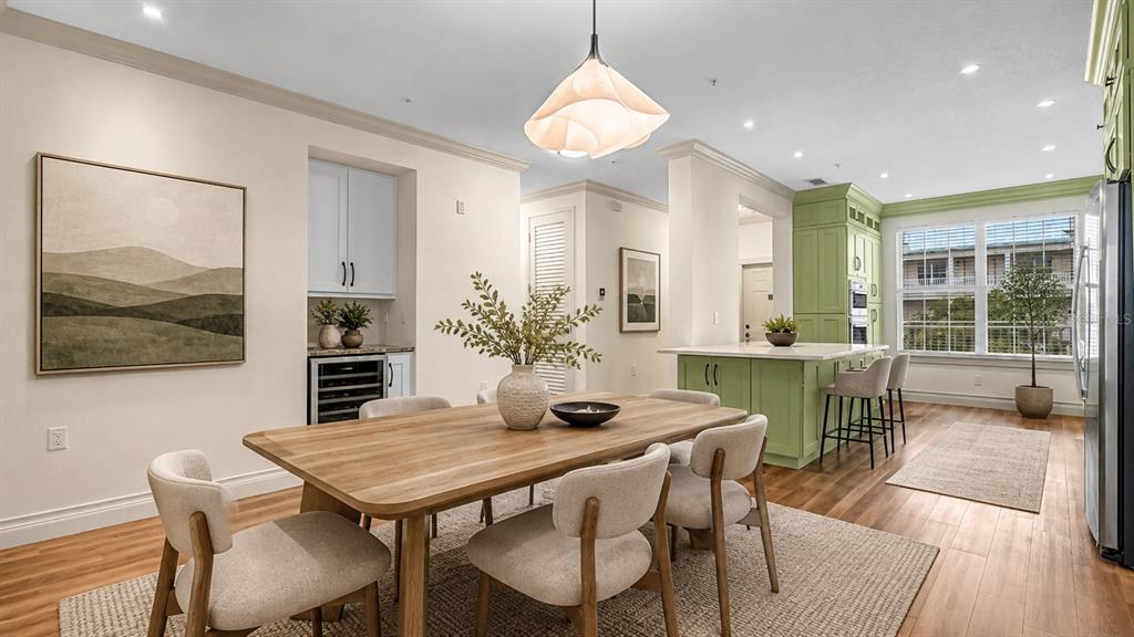 A dining area with a wooden table and chairs sits adjacent to a green kitchen island — 4286 ANISSA AVENUE UNIT 10-202, ORLANDO, FL